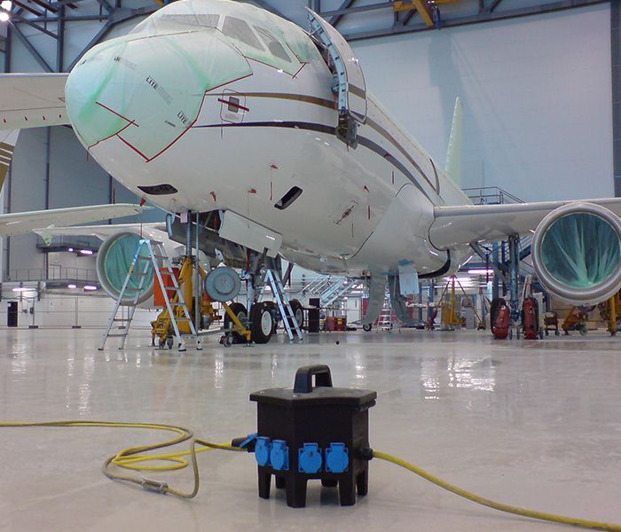 Mobiler Stromverteiler bei Wartungsarbeiten an einem Flugzeug im Hangar – sichere Stromversorgung in der Luftfahrt