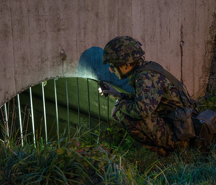 Soldier with flashlight during an inspection in the field - mobile work light for military operations