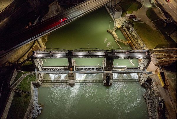 Aerial view of a dam at night with integrated LED lighting on weir and bridge structures