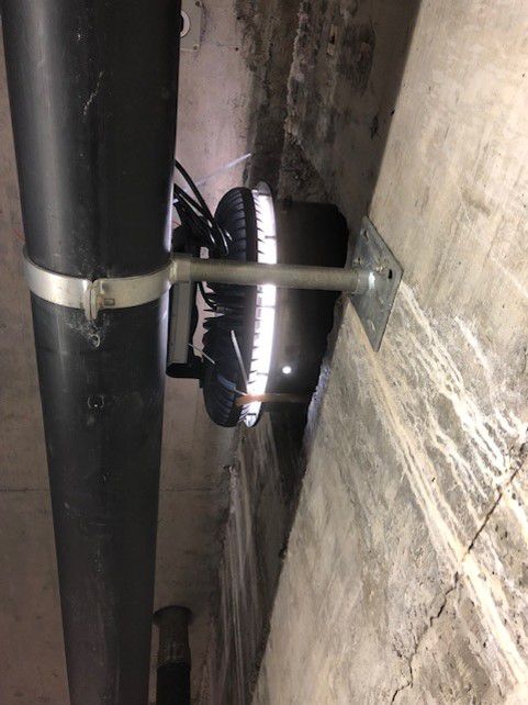 Luminaire industriel à LED pour l'éclairage de locaux humides, monté sur un mur en béton