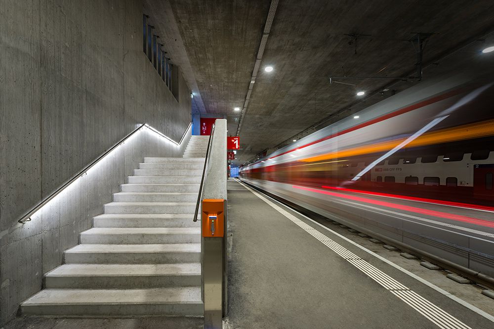 Illuminated station stairs with LED handrail and passing train - safe routing and modern lighting in the station platform