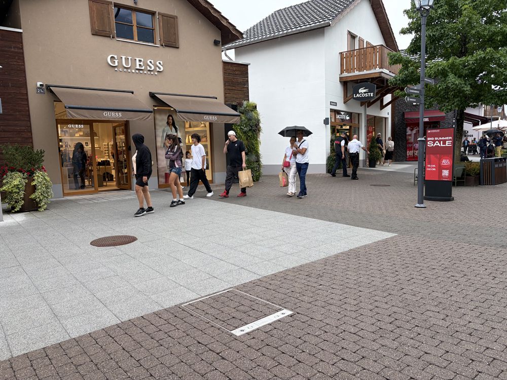 Place publique au centre d'un village avec bâtiments, piétons et infrastructures pour les espaces publics
