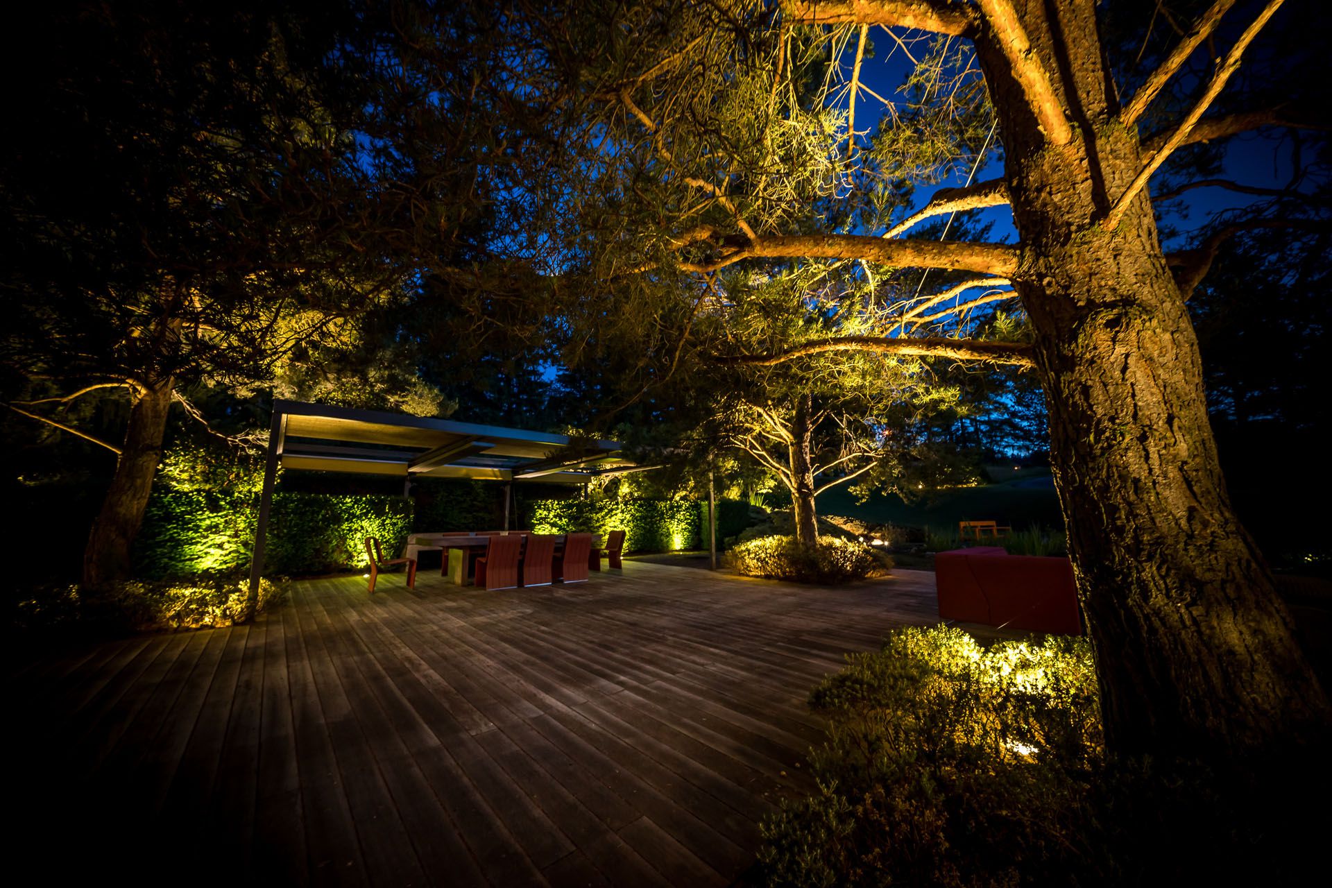 VisuLED garden lighting sets the scene for trees, plants and a patio with seating area and provides warm accent lighting