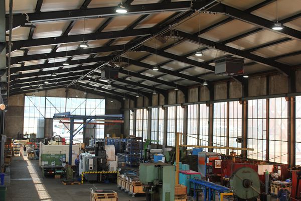 Large industrial hall with LED hall spotlights mounted on the ceiling - bright and efficient lighting for machine and production areas