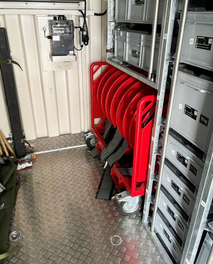 Mehrere rote Kabelrollen im Container verstaut, bereit für den mobilen Einsatz zur Stromversorgung
