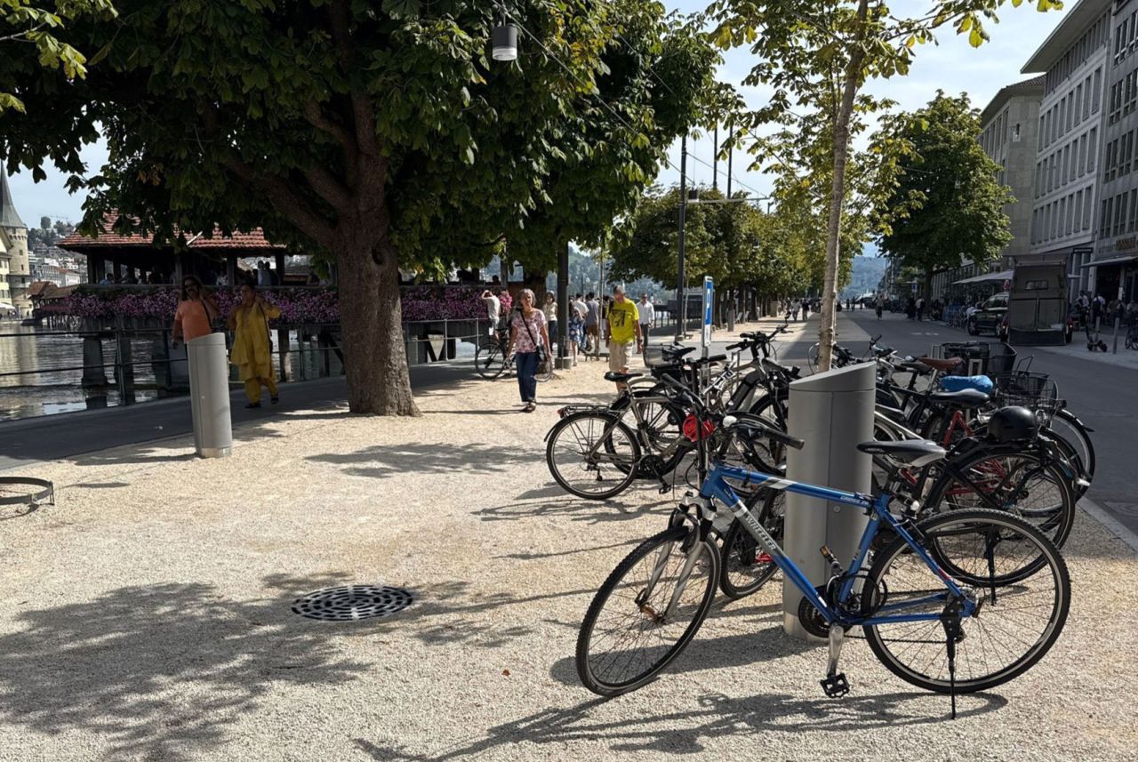 Two closed GIFAS power supply bollards along a tree-lined waterfront promenade with parked bicycles and pedestrians
