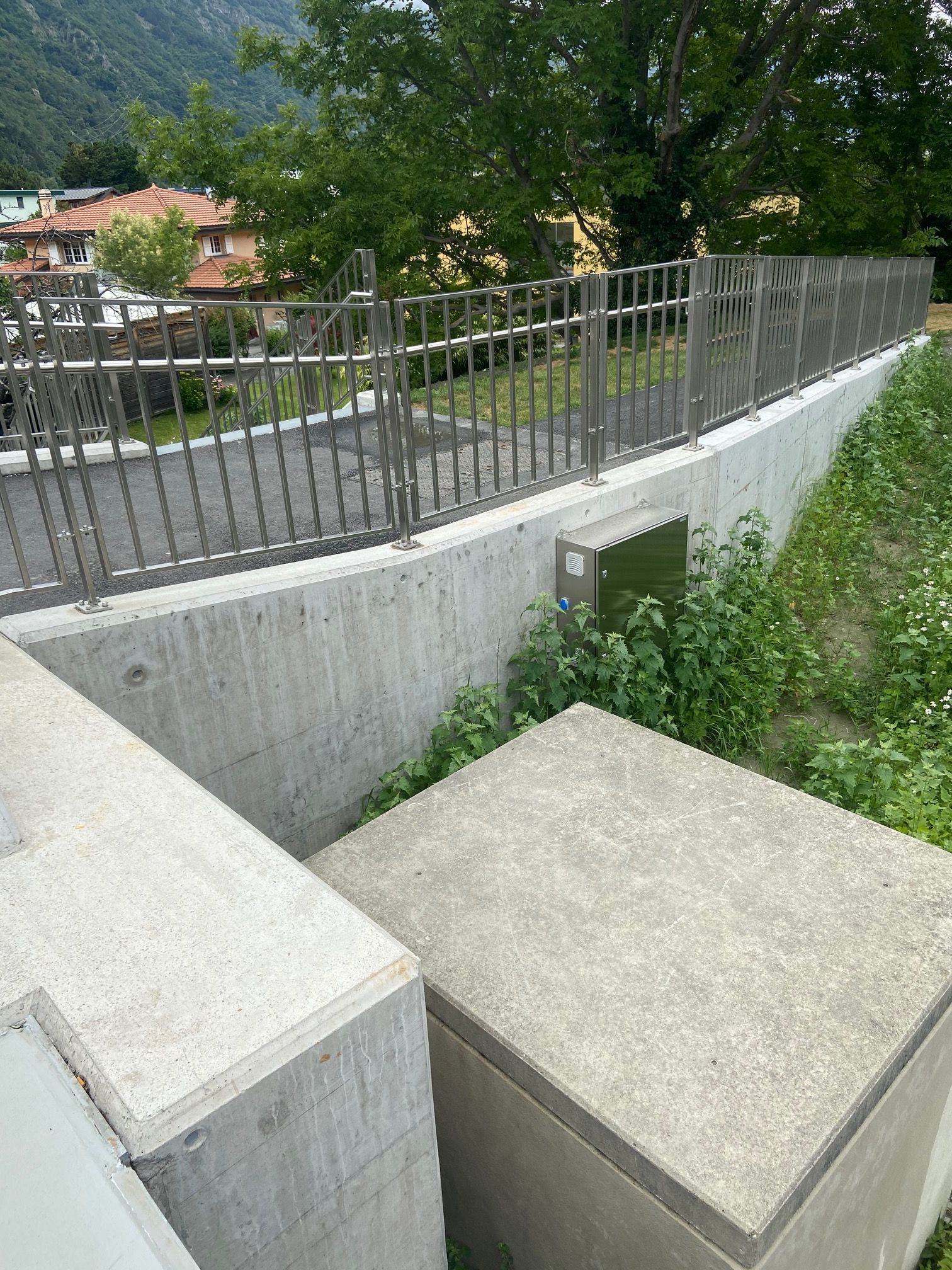 Installazione della ringhiera Inox42 lungo un percorso pedonale rialzato su una parete di cemento, predisposta per l'illuminazione integrata del percorso a LED a Martigny