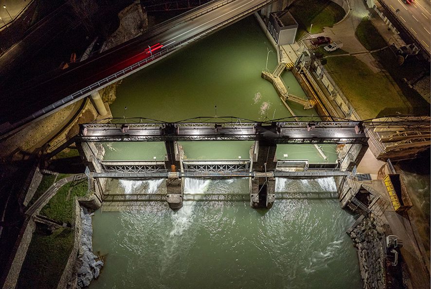 Aerial view of a dam at night with integrated LED lighting on weir and bridge structures
