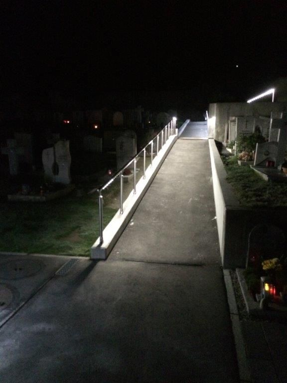 Illuminated path with LED handrail lighting at night at Glis cemetery
