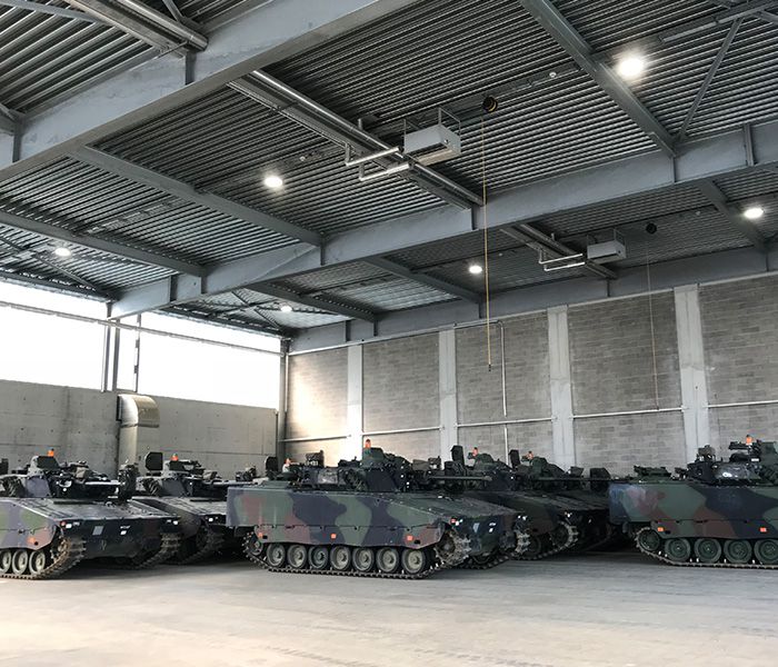 Military vehicles in a vehicle hall with lighting - Infrastructure and power supply for military facilities