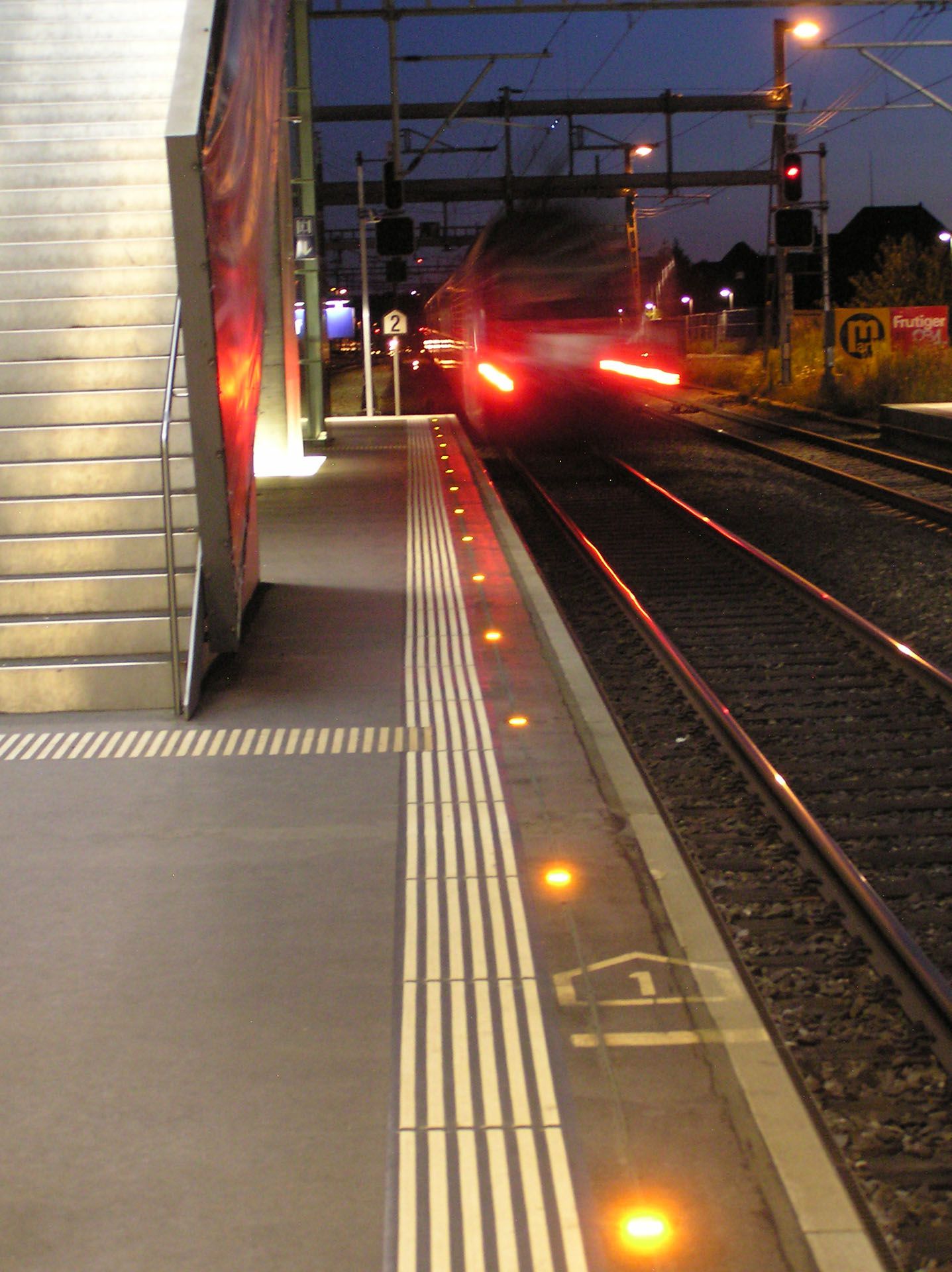 Active LED safety lighting on the platform edge at night with an incoming train at Wankdorf station