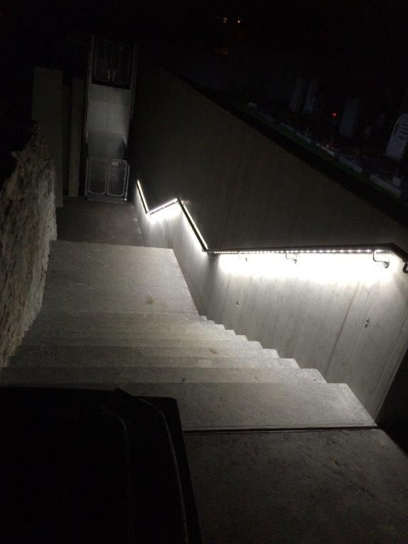 Illuminated staircase with LED handrail lighting at night at Glis cemetery