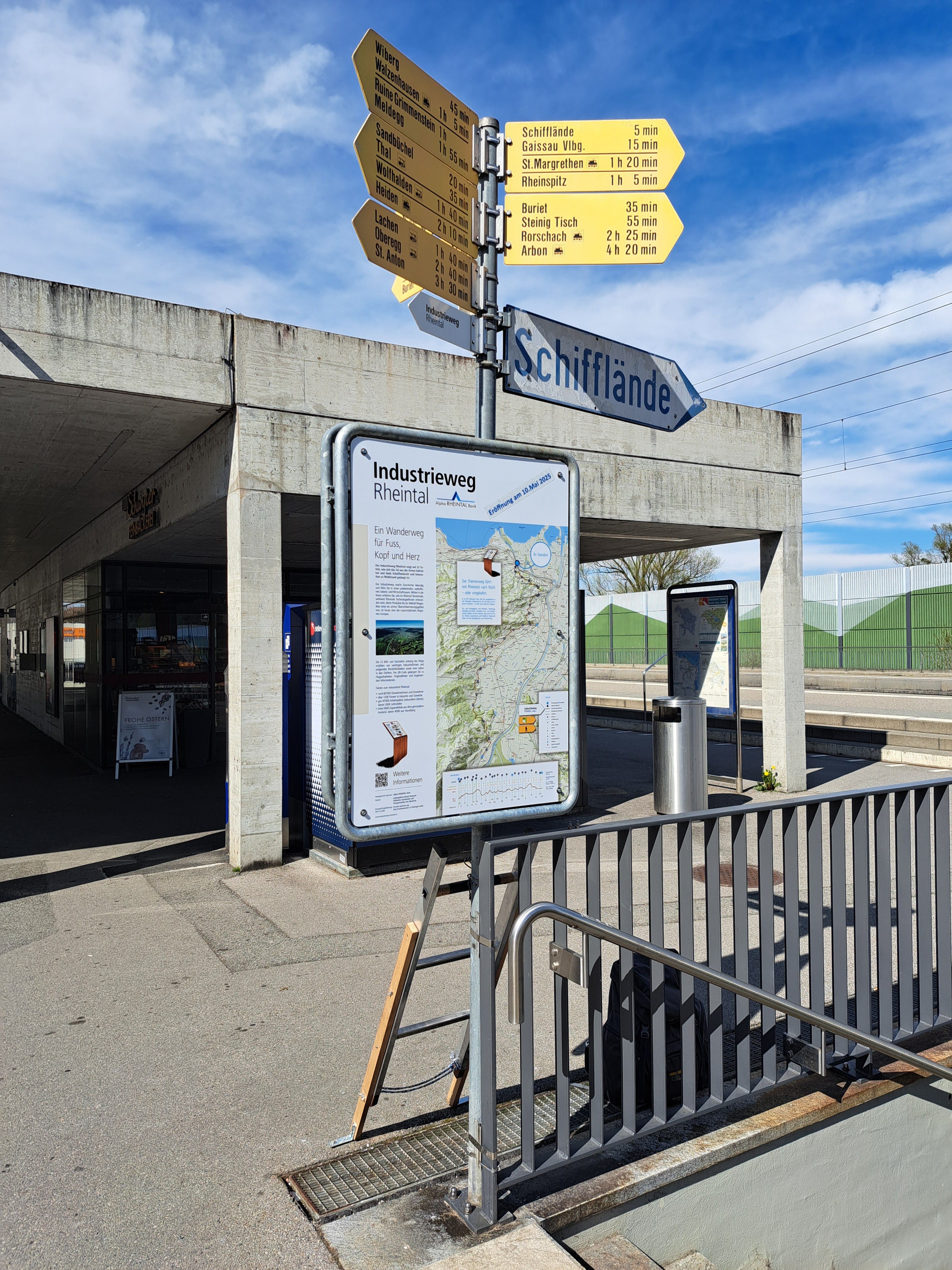 Wegweiser und Informationstafel im öffentlichen Raum bei Unterführung entlang eines Industriewegs