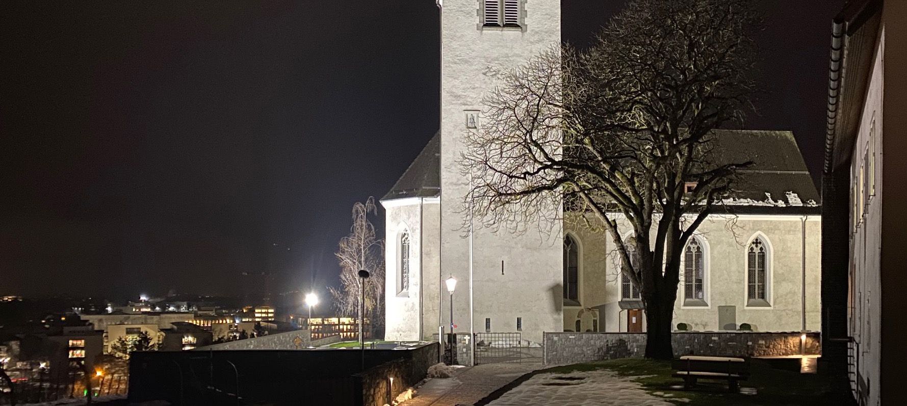 Illuminazione notturna a LED della piazza di una chiesa con gli apparecchi DeltaLUXX su una piazza pubblica a Gamprin