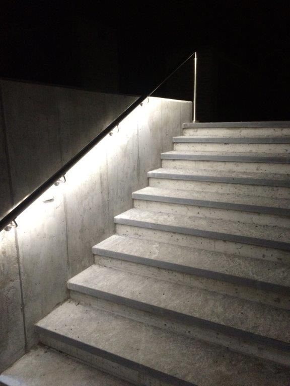 Illuminated handrail with integrated LED light line on a concrete staircase at Glis cemetery