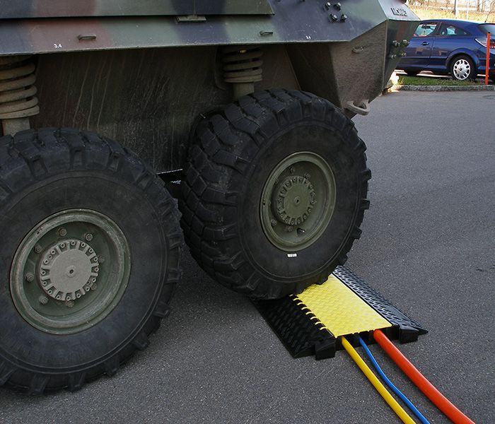Military vehicle drives over cable bridge to protect power cables - safe cable routing in the operational area