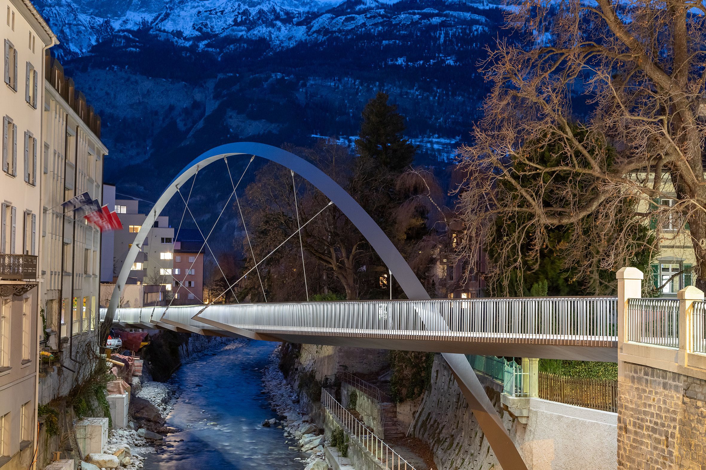 LaneLED illuminated pedestrian bridge over the Plessur in Chur provides safe guidance at dusk against an alpine backdrop