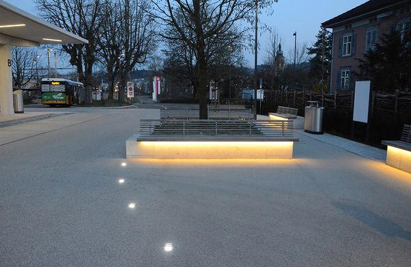Öffentlicher Platz mit integrierten Bodenleuchten und beleuchteten Sitzbänken – sichere und stimmungsvolle LED-Beleuchtung im Aussenraum