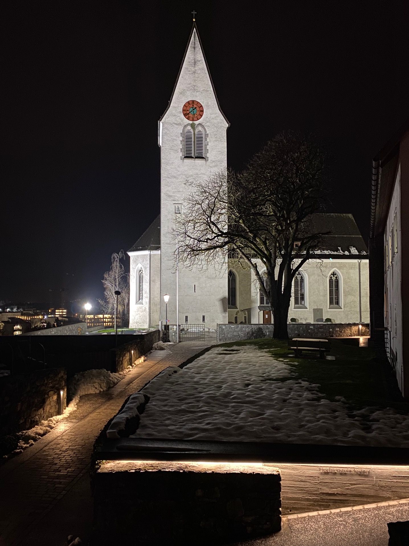 Illuminazione notturna a LED di una chiesa con apparecchi DeltaLUXX in una piazza pubblica a Gamprin