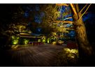 VisuLED garden lighting sets the scene for trees, plants and a patio with seating area and provides warm accent lighting