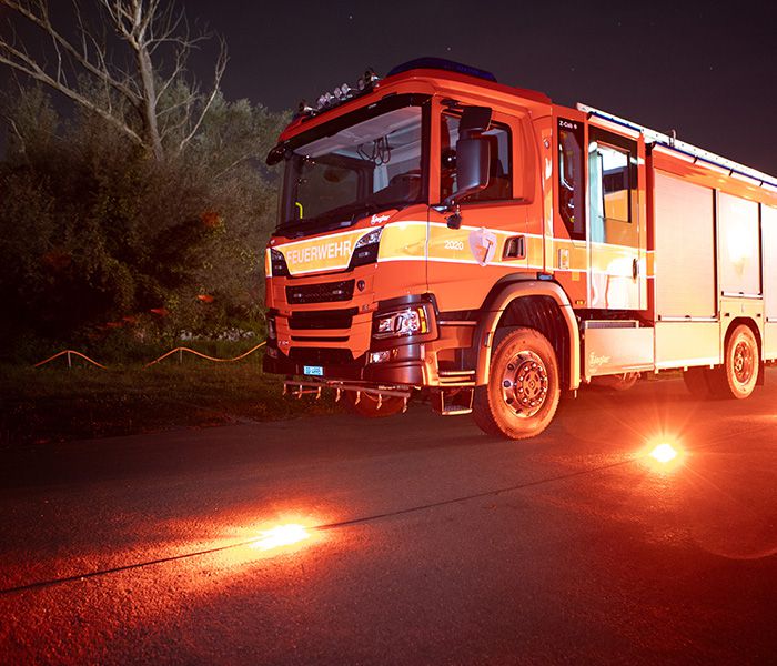 Feuerwehrfahrzeug bei einer nächtlichen Übung mit Warnleuchten zur Absicherung der Einsatzstelle auf der Strasse