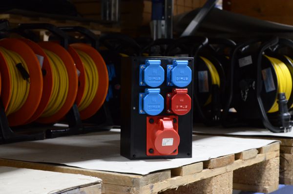 Mobile power distributor with CEE sockets in the warehouse in front of cable reels for power distribution in industrial environments