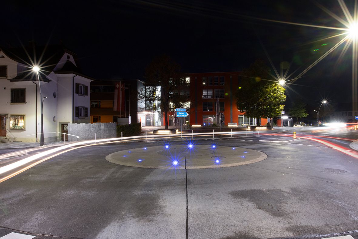 Kreisel bei Nacht mit blauer LED-Bodenbeleuchtung zur klaren Verkehrsführung und erhöhten Sicherheit im Strassenraum