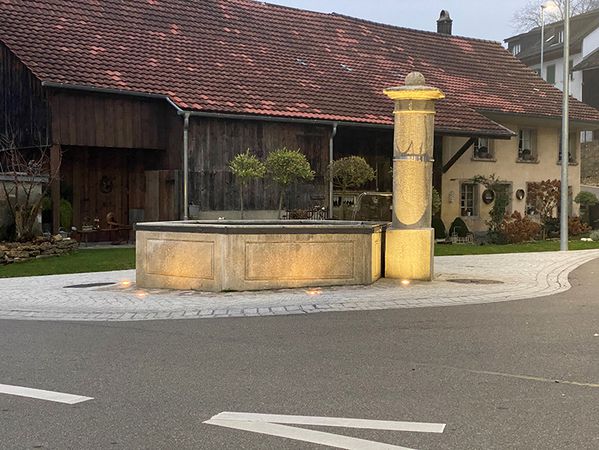 LED exterior lighting of a village fountain in a public square with uniform and warm illumination