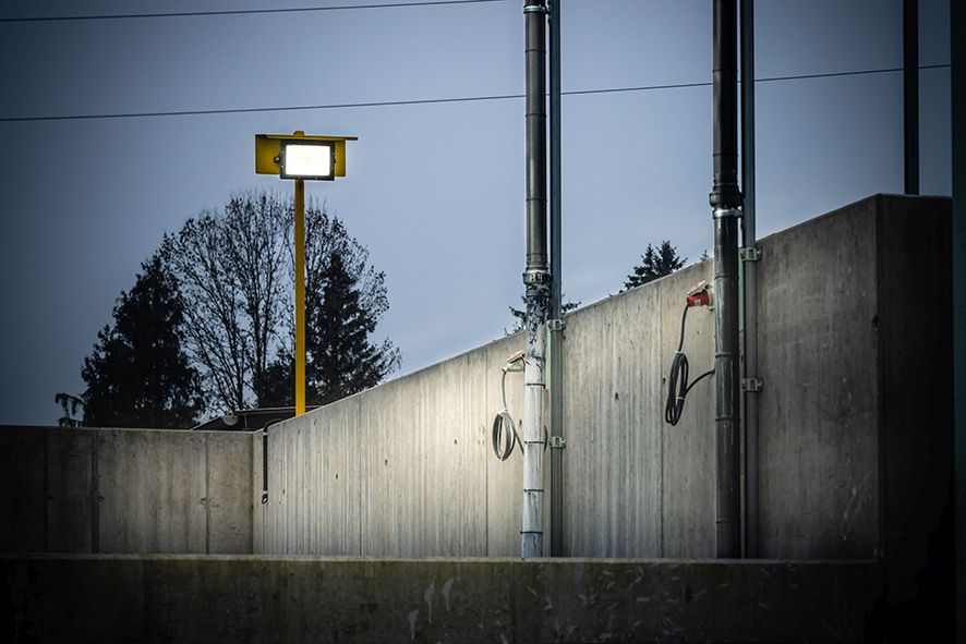 Il faretto LED AlphaLUXX su palo giallo fornisce un'illuminazione esterna brillante per un impianto industriale e migliora la visibilità durante i processi di lavoro
