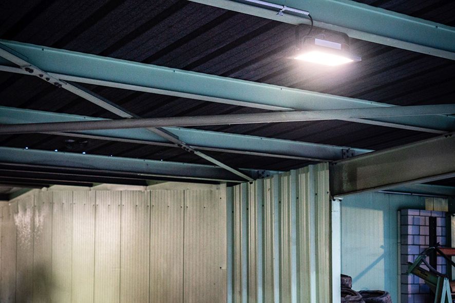 I faretti LED AlphaLUXX installati sul soffitto di un capannone industriale illuminano in modo brillante e uniforme le aree di lavoro e le strutture di lavaggio