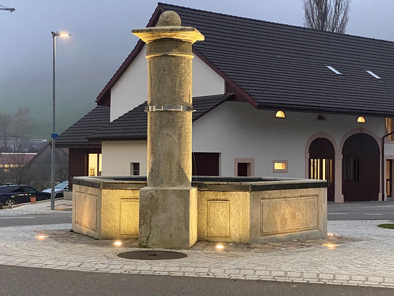 Éclairage extérieur à LED d'une fontaine de village sur une place publique avec un éclairage uniforme au crépuscule