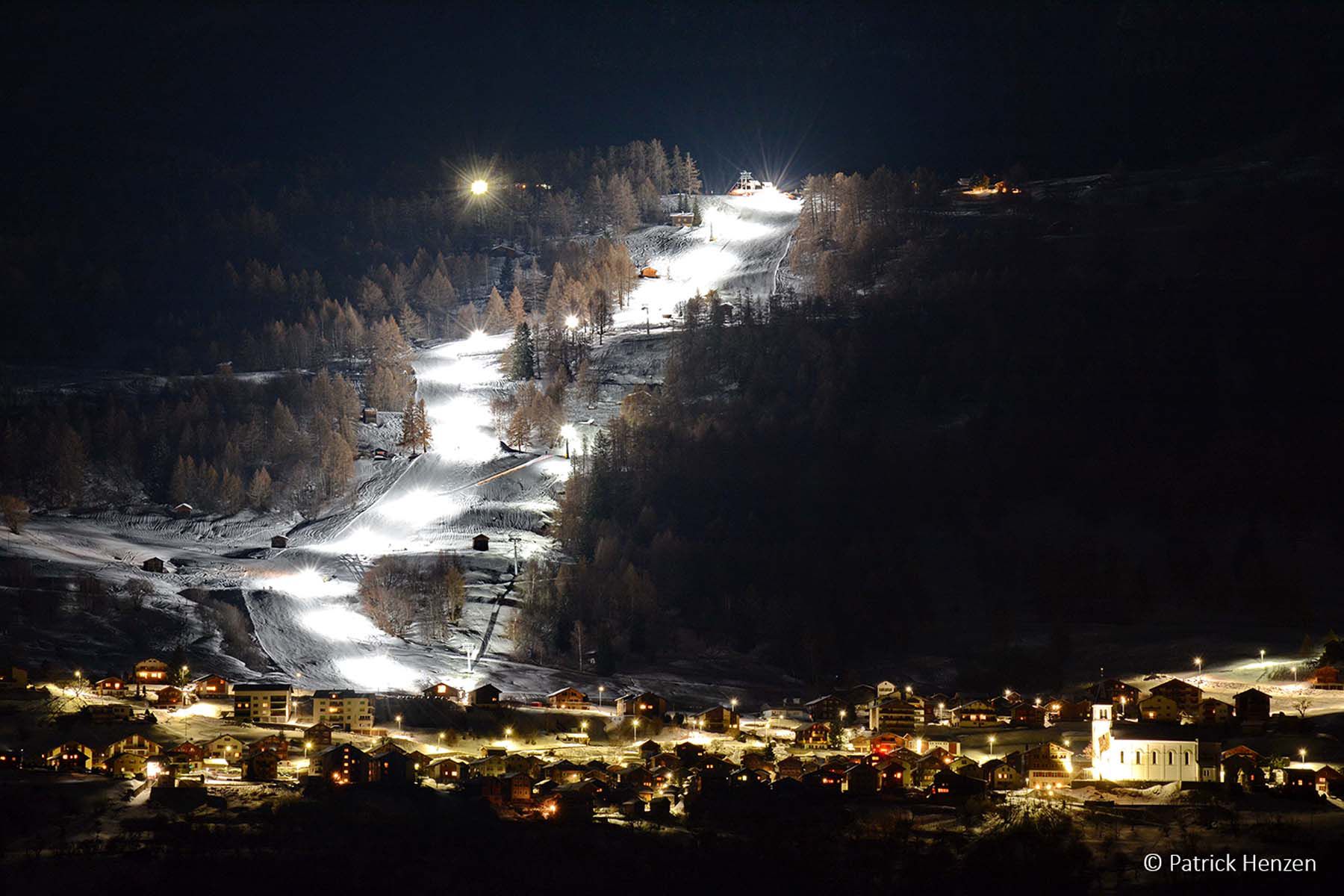 Beleuchtete Skipiste bei Nacht mit leistungsstarker LED-Beleuchtung für sicheren Betrieb der Bergbahn