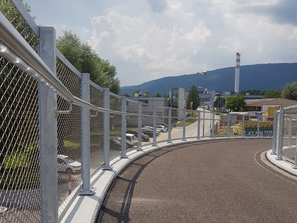 Fahrradrampe mit Metallgeländer und Sicherheitsnetz in einem Industriegebiet – sichere Infrastruktur für Veloverkehr