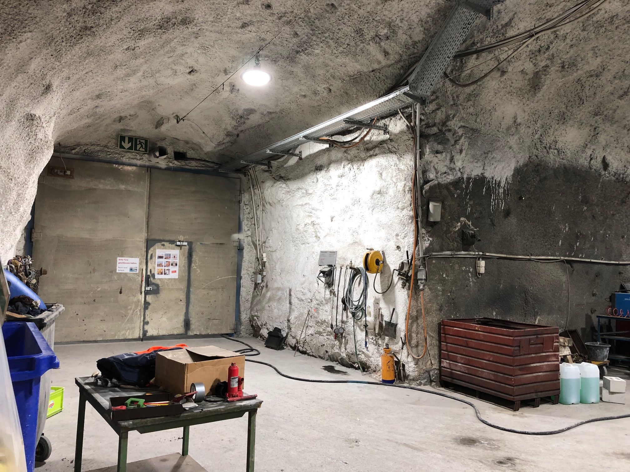 Work area in the test gallery with LED ceiling spotlights, tools and robust rock environment - well-lit underground infrastructure