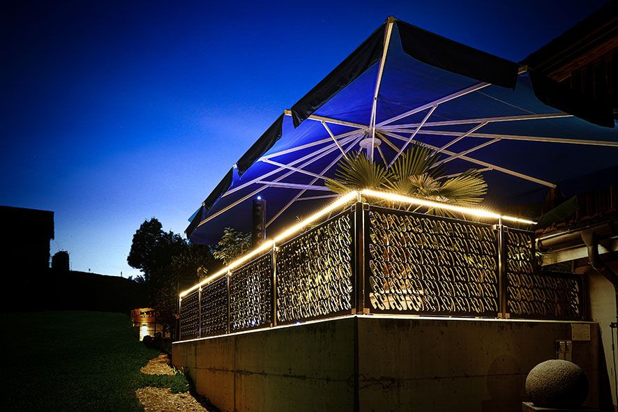 Area salotto da giardino illuminata d'atmosfera con illuminazione a LED del corrimano sulla ringhiera decorativa - elegante illuminazione d'accento nell'area esterna