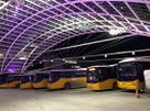Illuminated bus station with Postbuses and installed power supply under modern roof construction