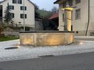 Éclairage extérieur à LED d'une fontaine de village sur une place publique avec un éclairage d'ambiance au crépuscule