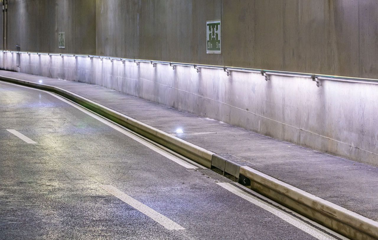 Tunnel routier avec éclairage LED le long du mur et voie de maintenance et d'évacuation éclairée pour une sécurité accrue